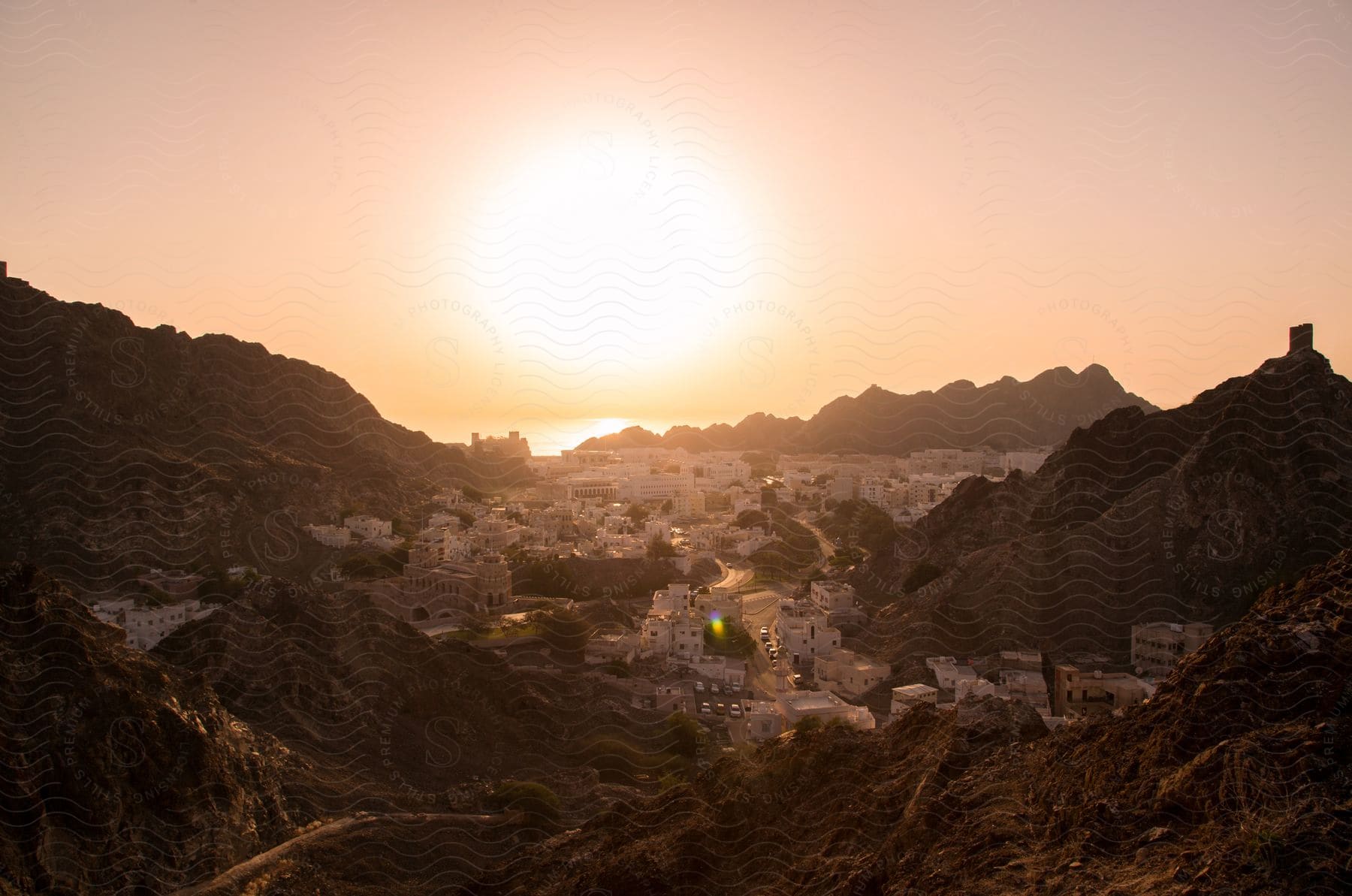 A european town with white buildings surrounded by mountains at sunset