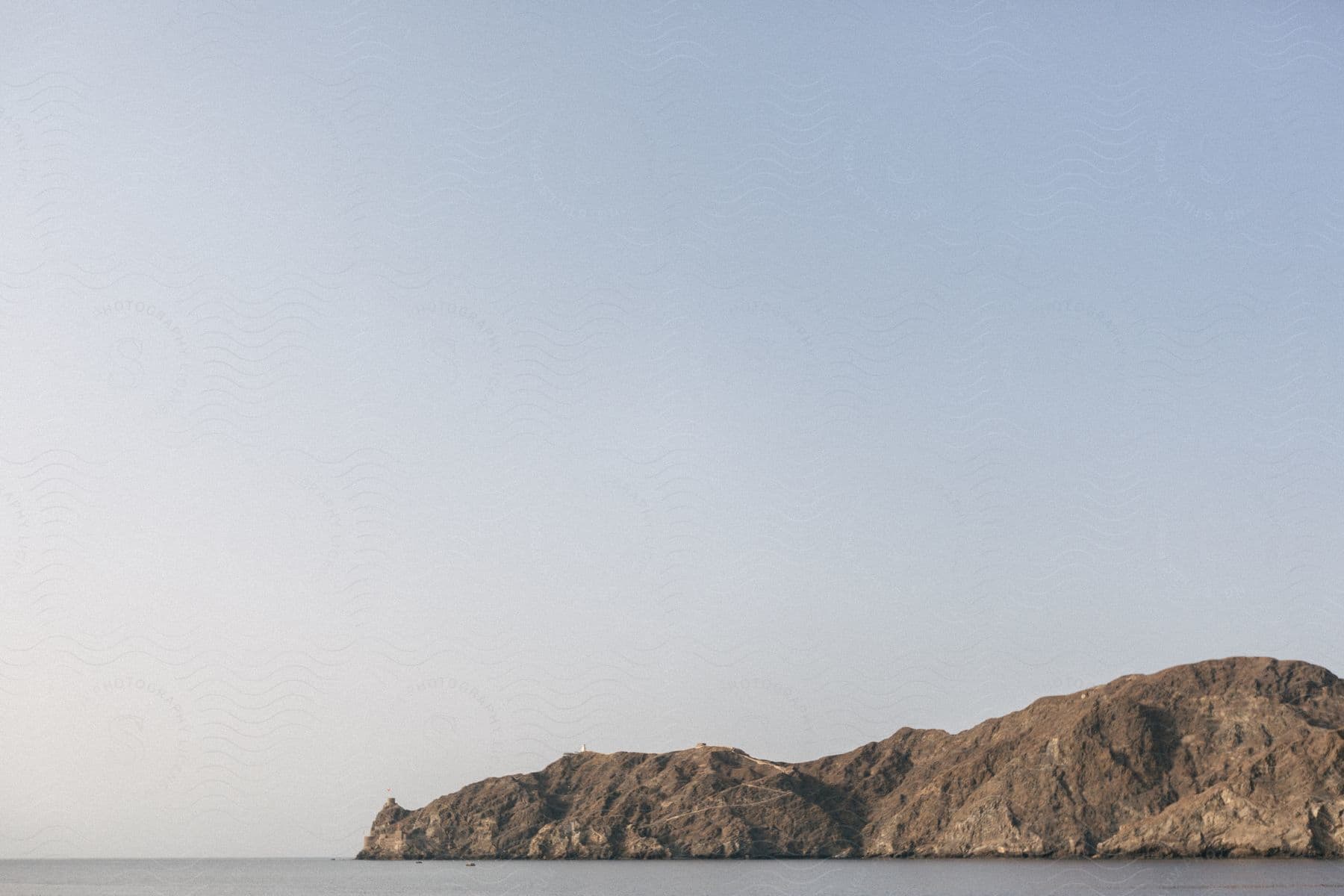 Mountains meet the shoreline under a gray sky