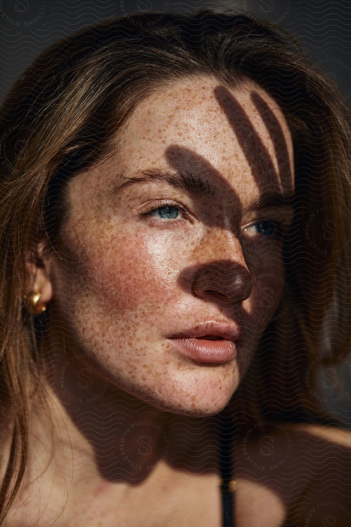 A woman with black hair and freckles looking straight ahead with a neutral expression