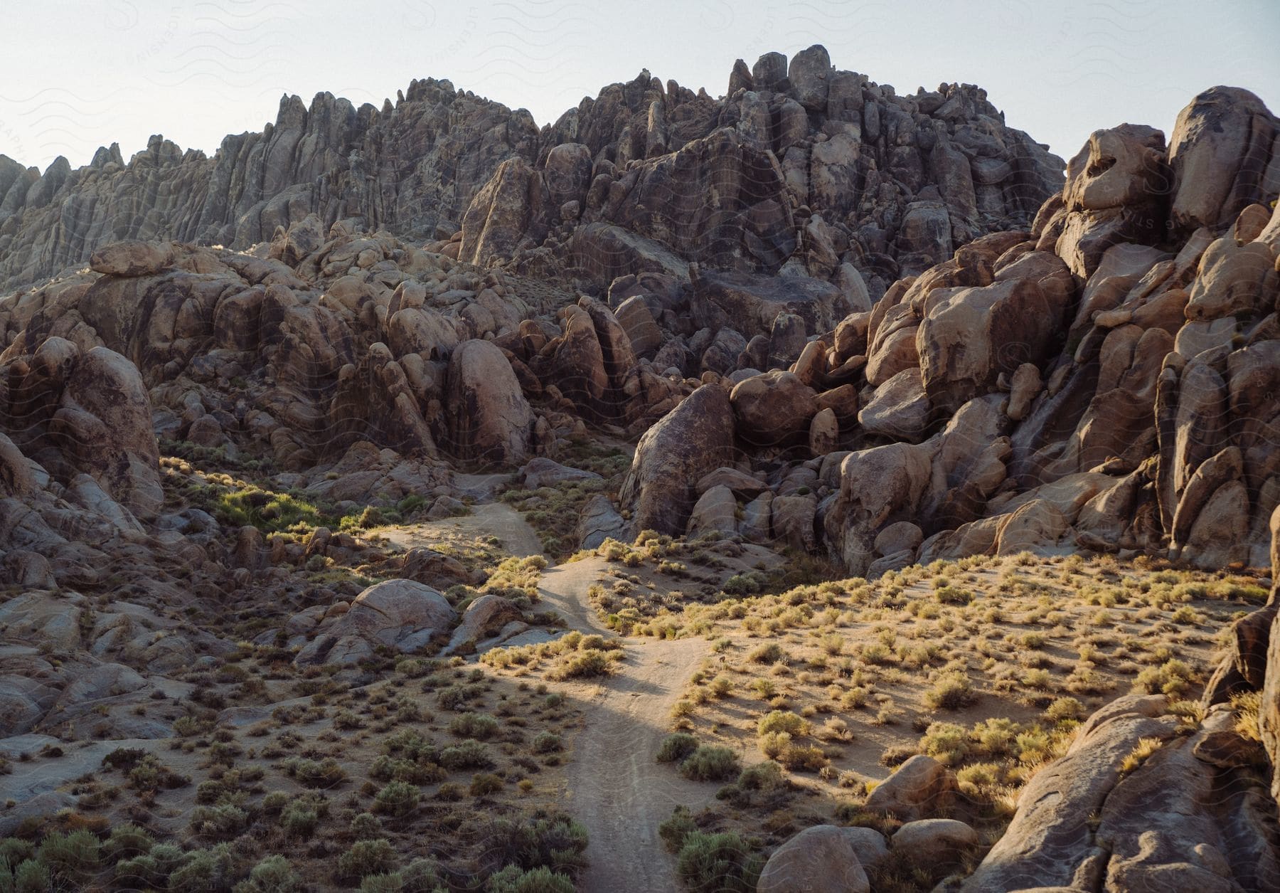 A dirt road across grassy hills leading into large rock formations