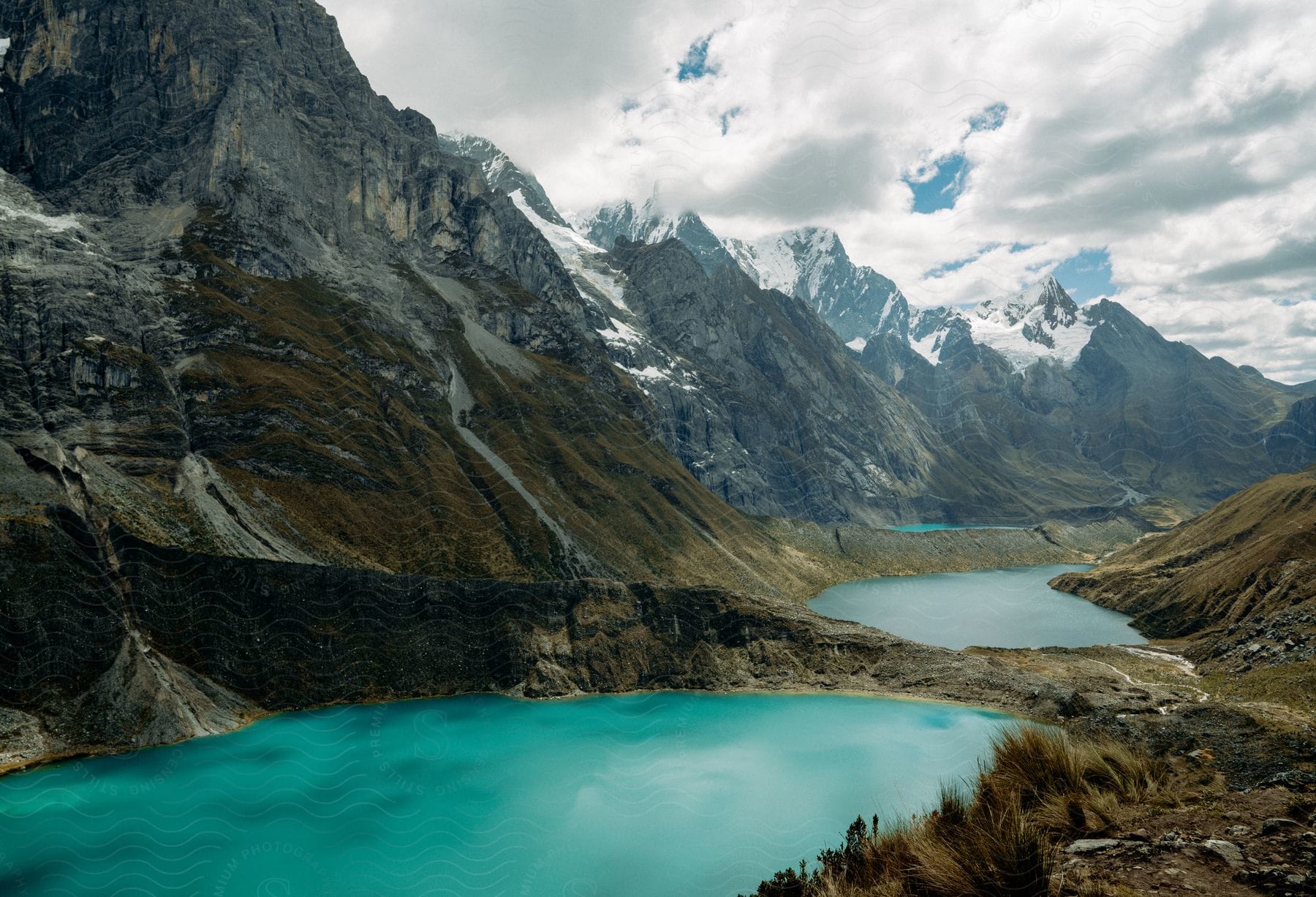 A large mountain with peaks of snow and ice with small bodies of water at the bottom