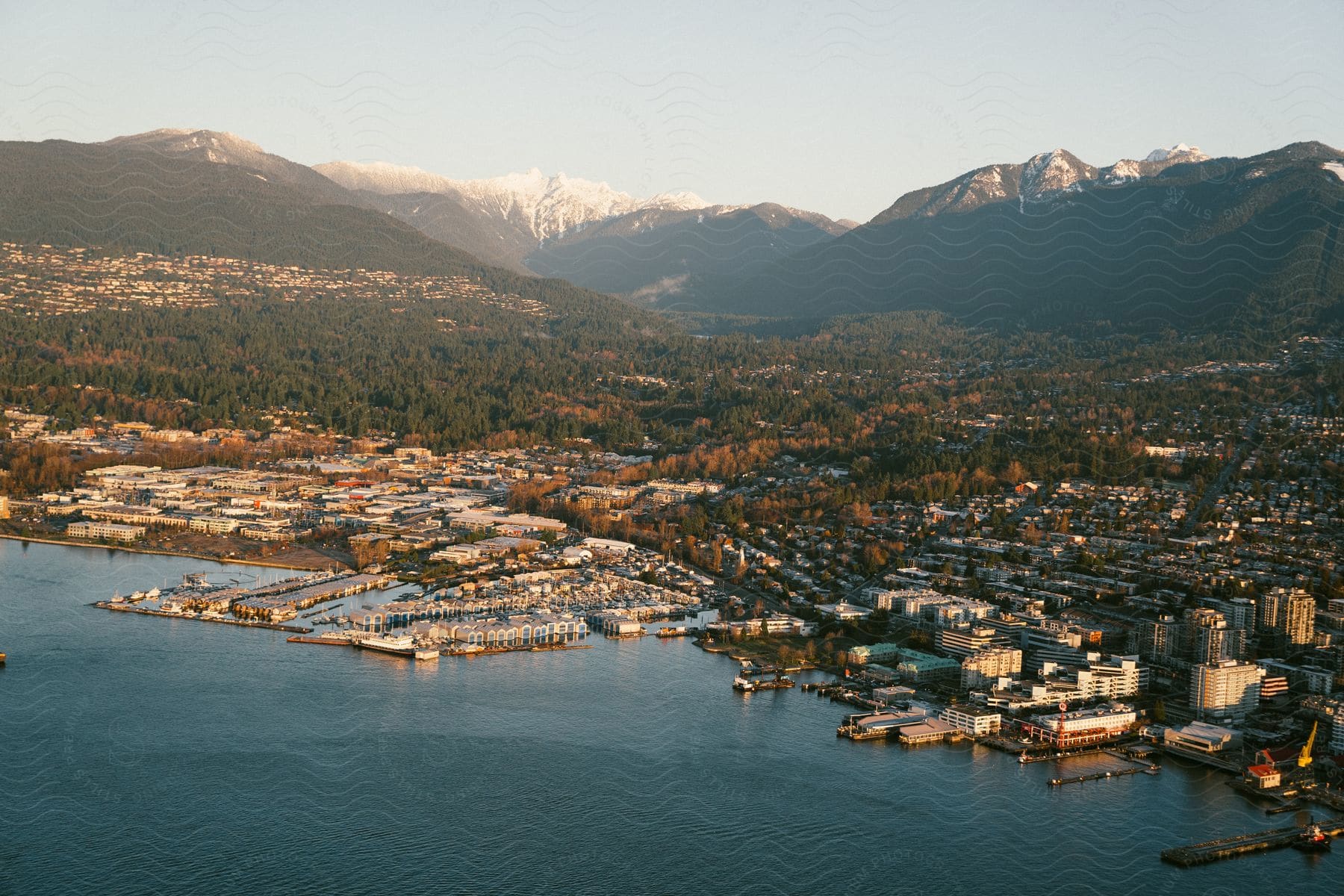 Aerial view of a city with mountains and a pier by the water