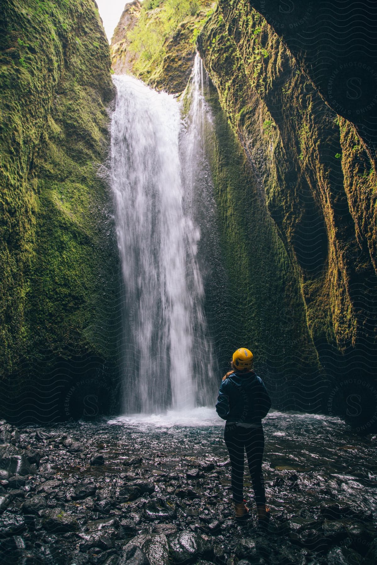 A woman admiring a waterfall surrounded by large rocks in iceland