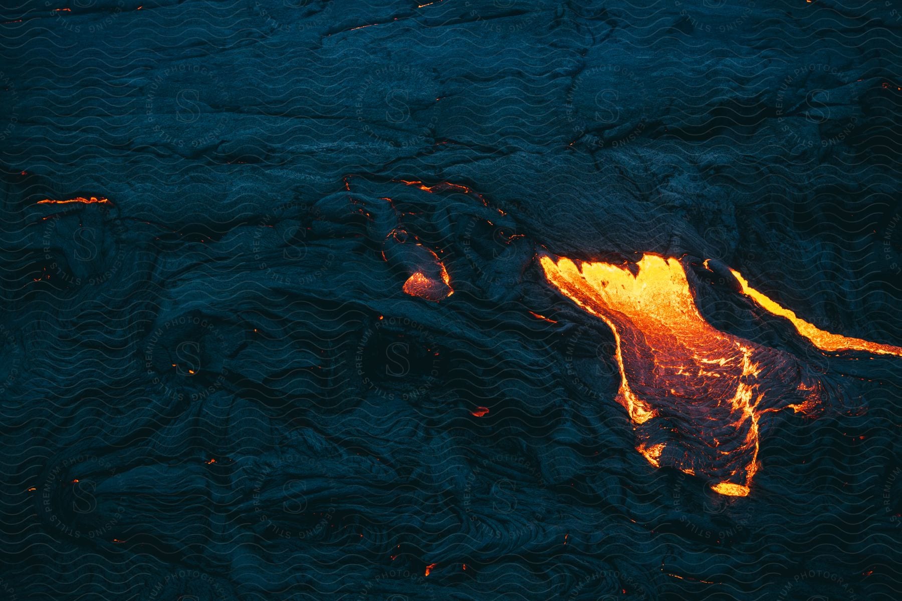 Stock photo of hot lava glows in the darkness as it flows from an erupting volcano in iceland