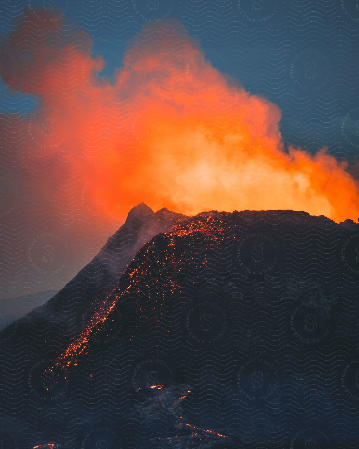 Glowing red smoke rises from an erupting volcano as molten hot lava flows in iceland