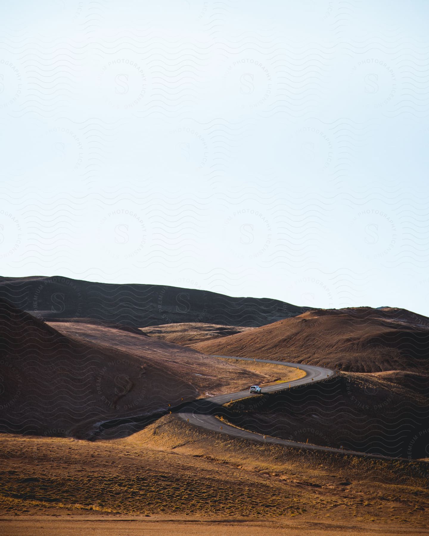 Distant car driving up on winding road in the desert