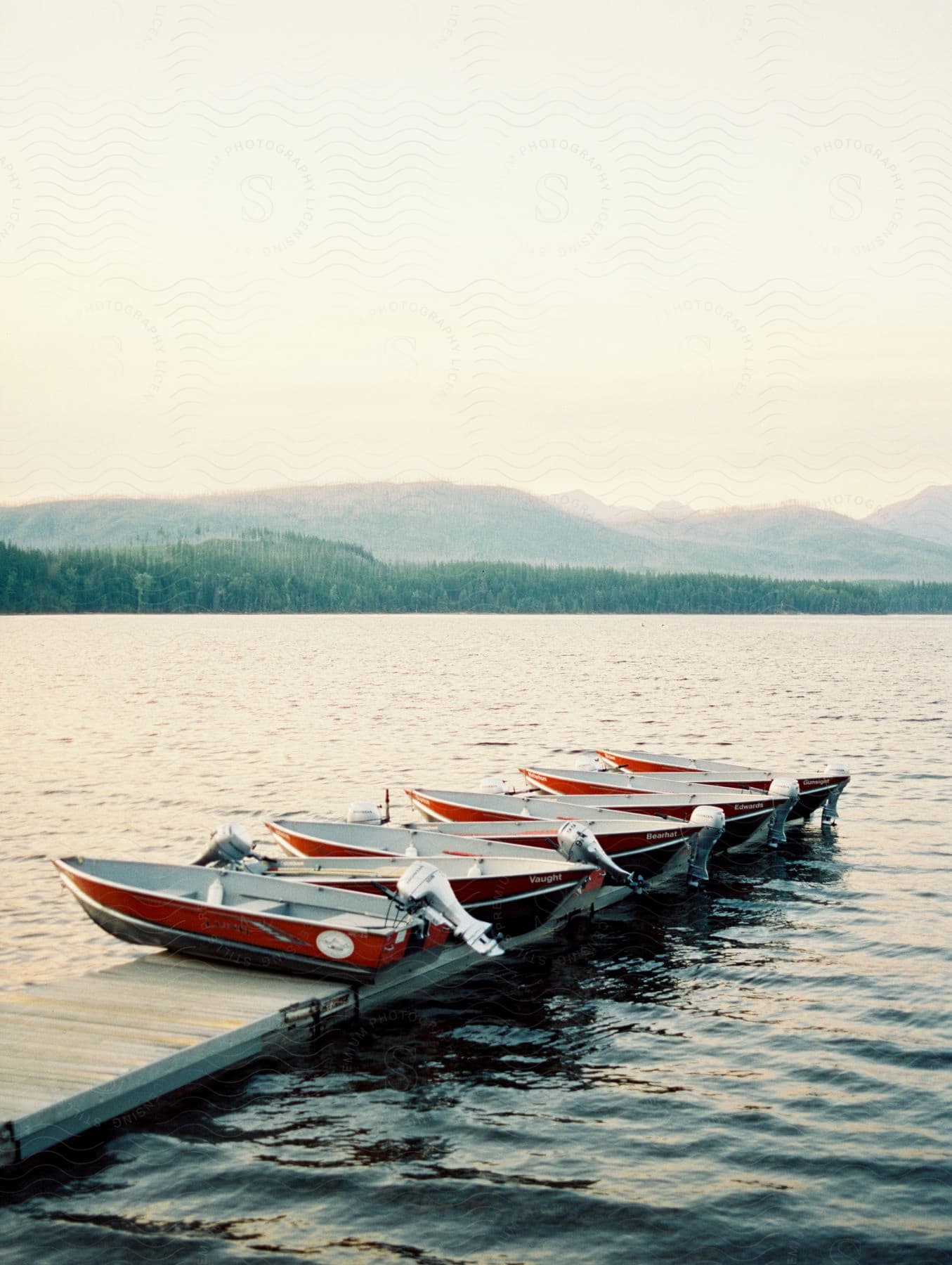 Boats parked on a narrow wooden dock on a lake