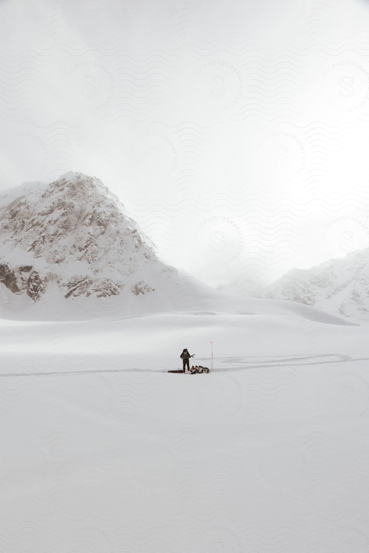 Person standing in snow covered plateau with snow covered mountains behind them in talkeenta alaska