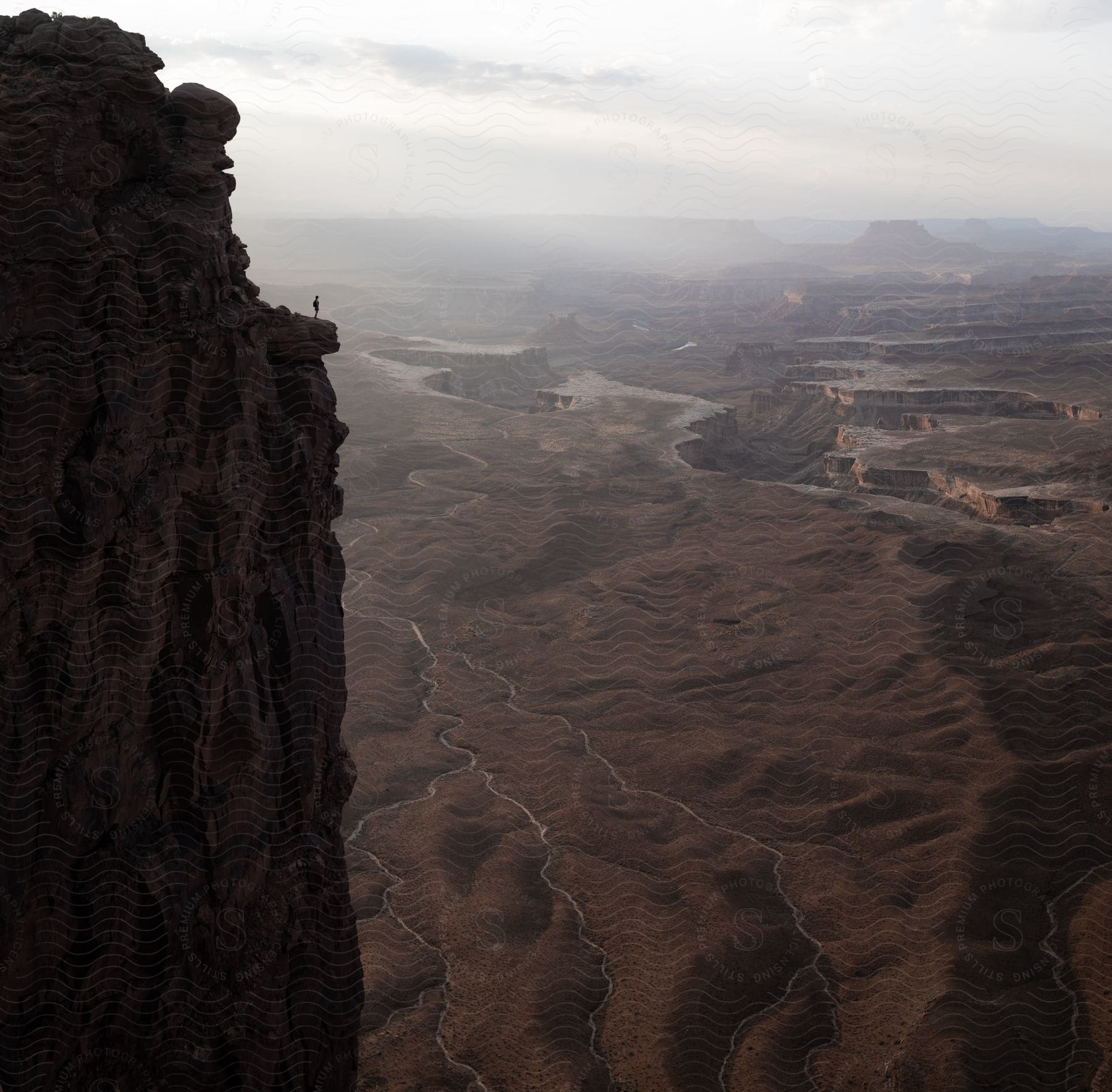 Mountainous landscape with person on cliff edge looking over ravines