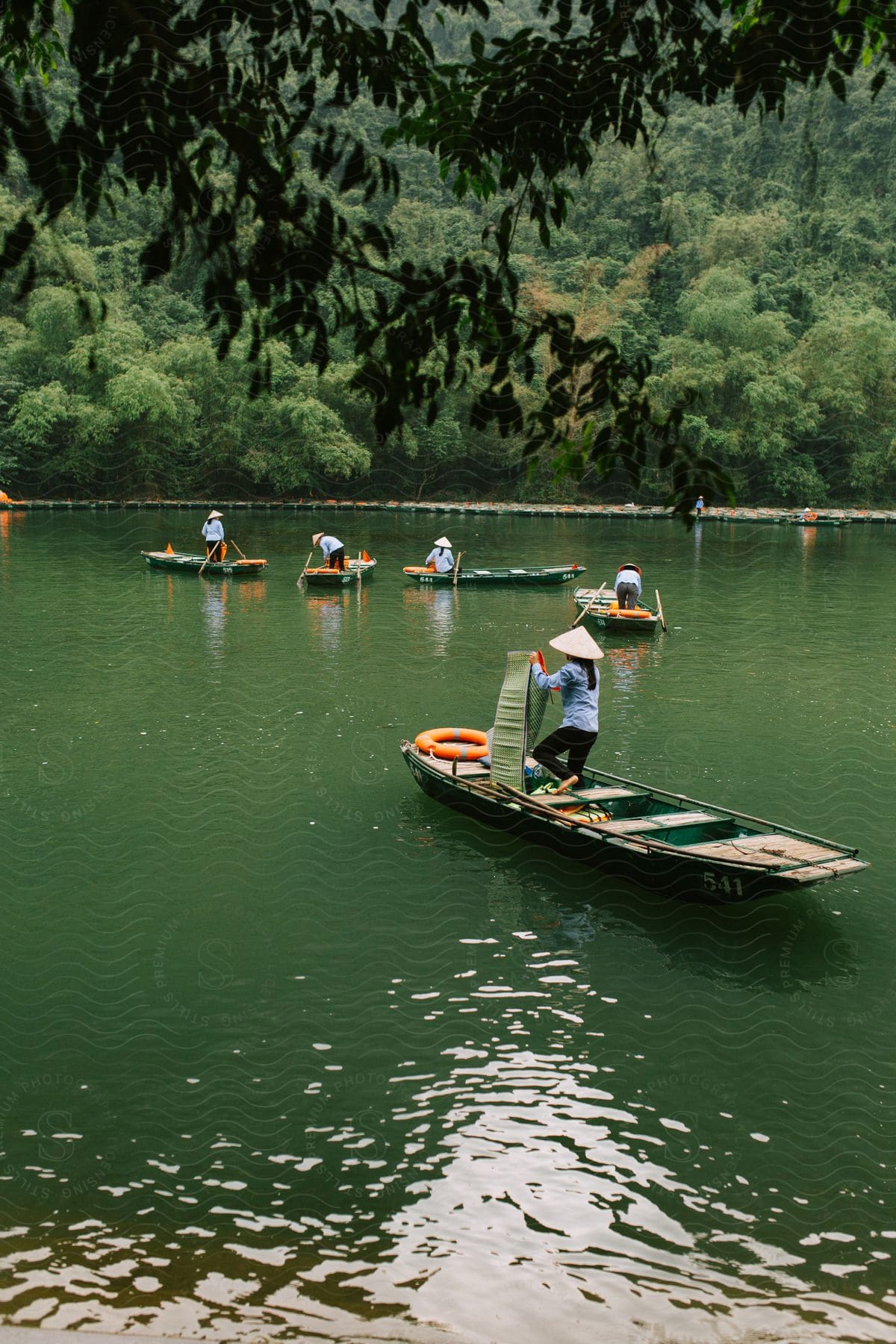 A group of people in canoes on a lake with forest in the background