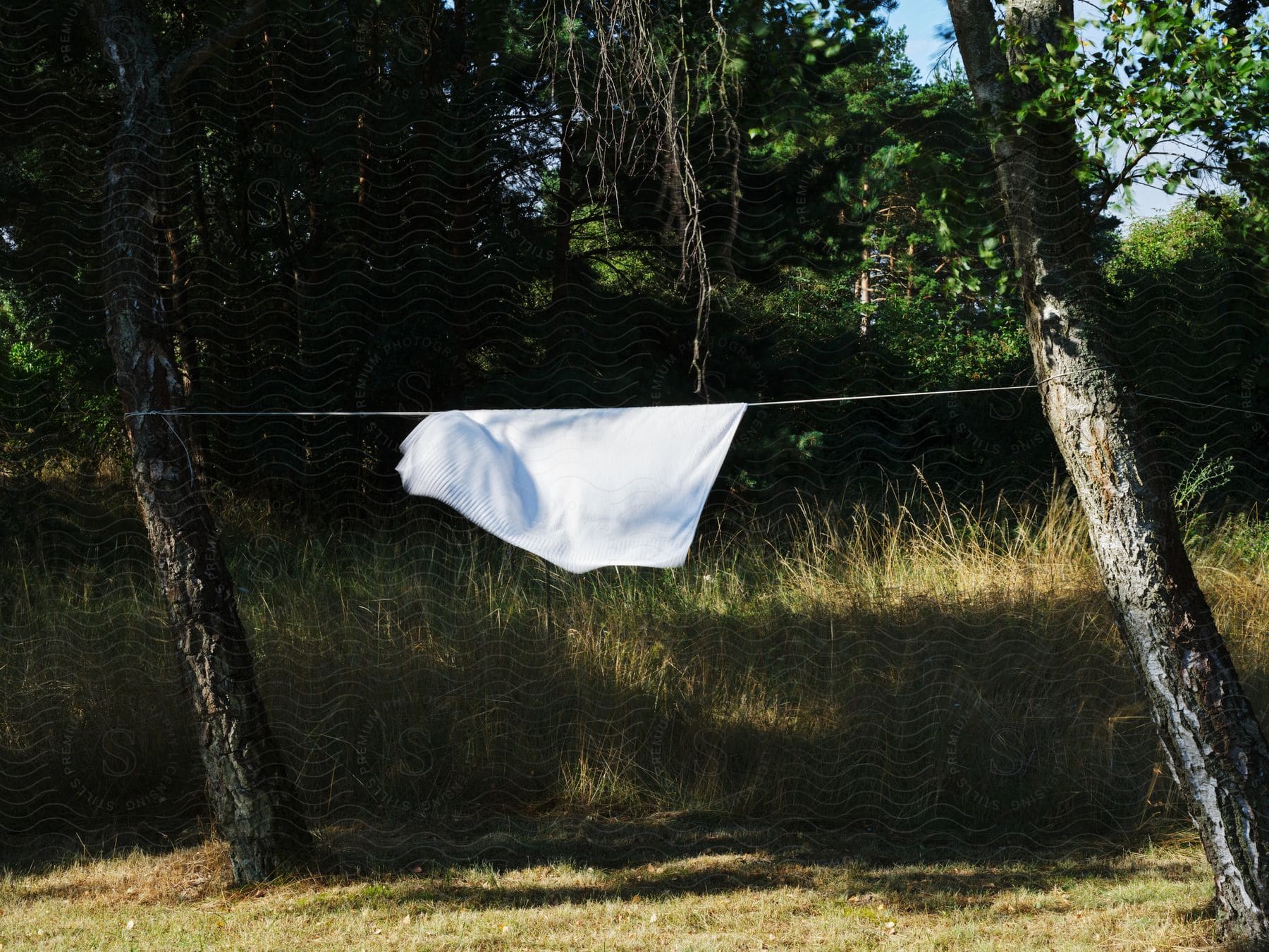 A white blanket hanging on a clothing line outside in skåne sweden during the summer