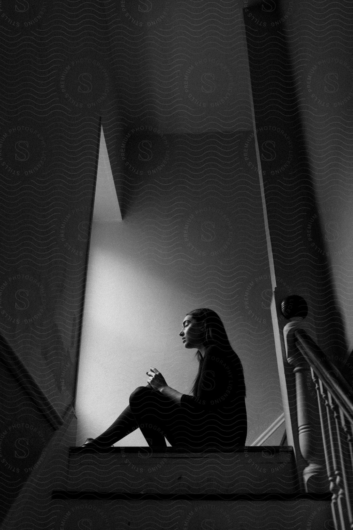 A woman sits on top of a staircase indoors
