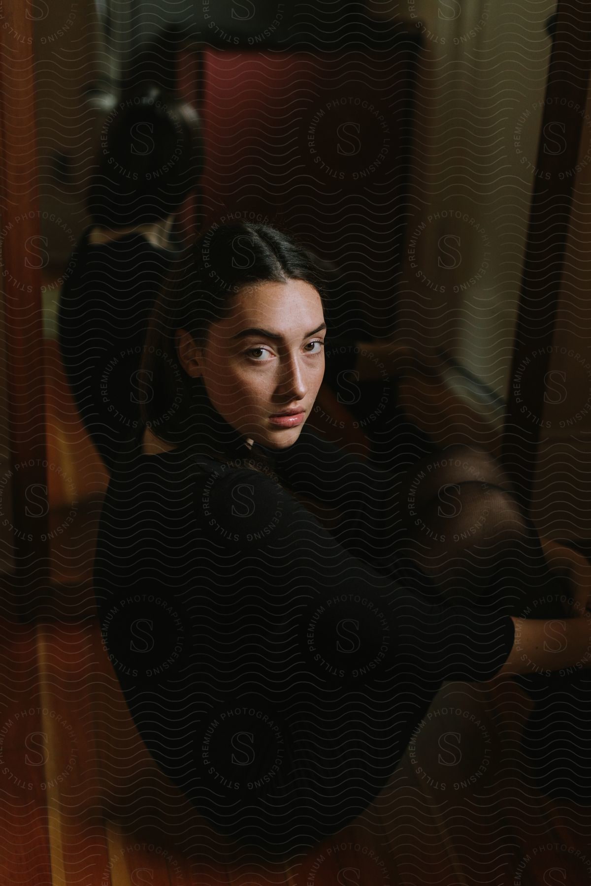 One person with black hair standing against a wooden background