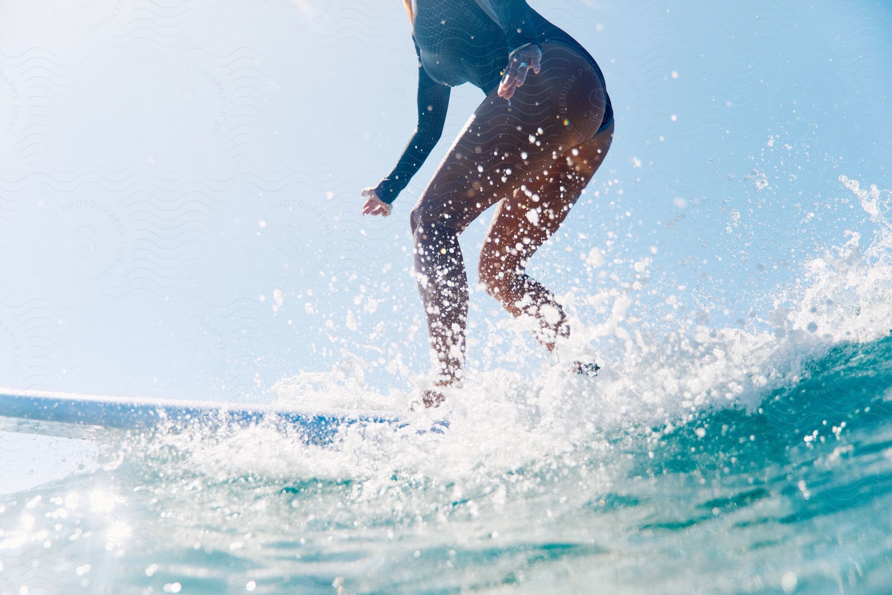 A female surfer rides a wave on a surfboard and gets sprayed by sea mist