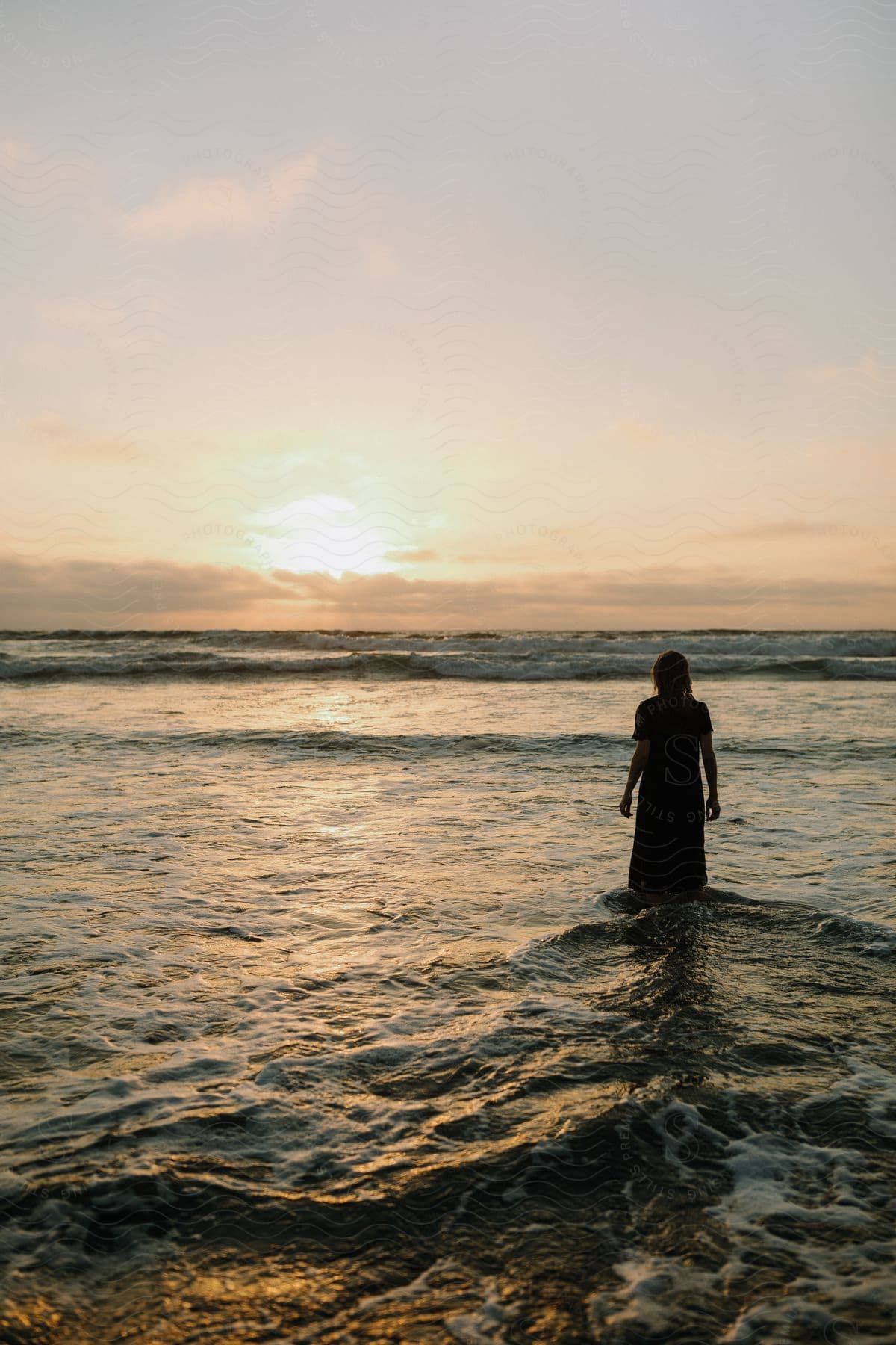Woman walking into the sea towards the sun
