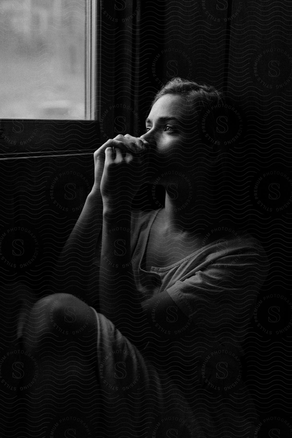 A female sits next to a window