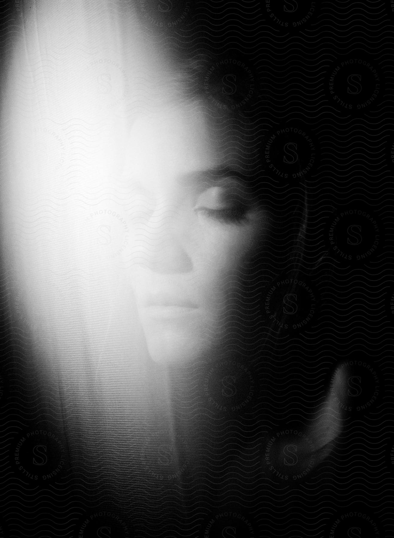 Black and white photograph of a womans face indoors with low key lighting