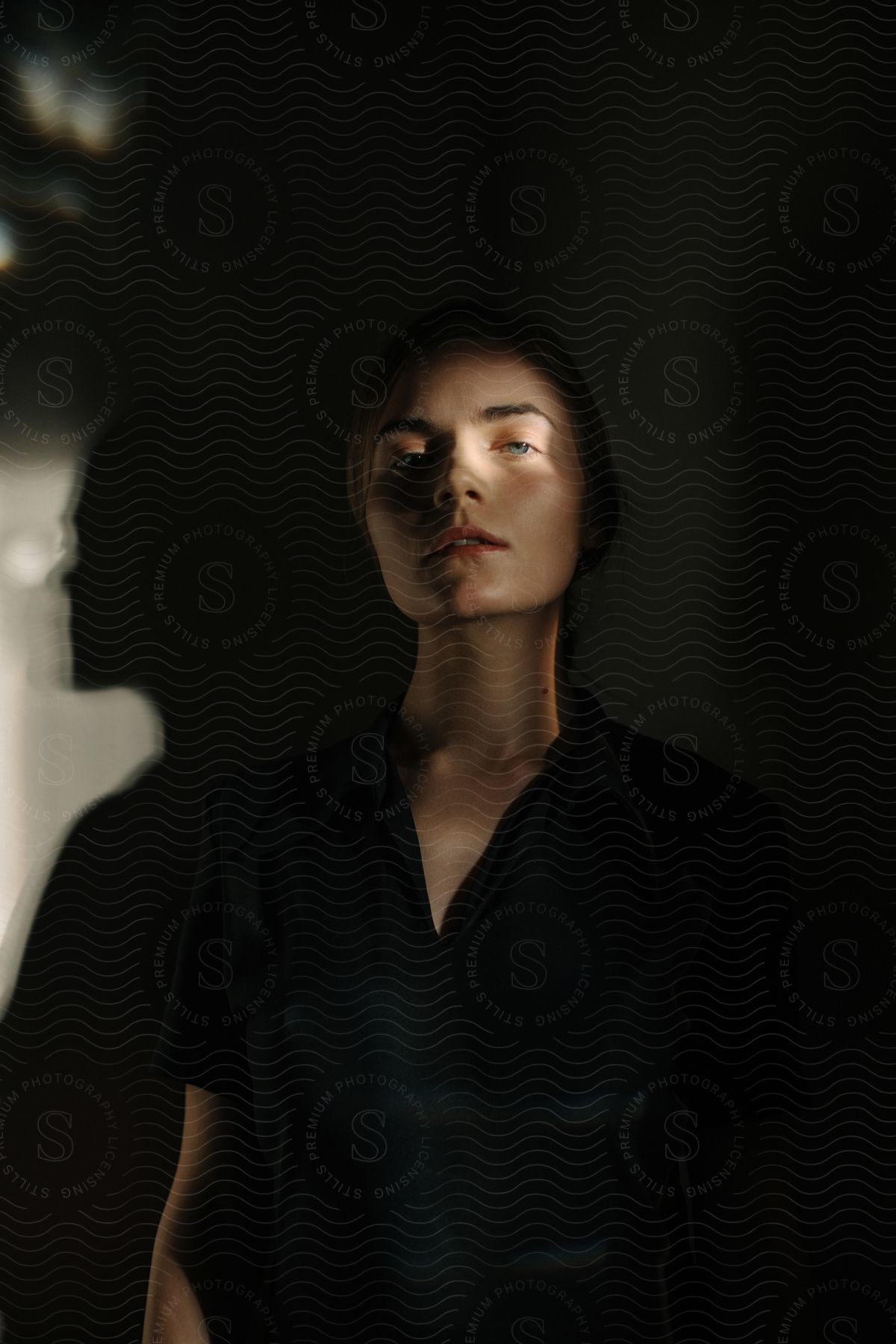 A woman dressed in black with her shadow reflected on the nearby wall