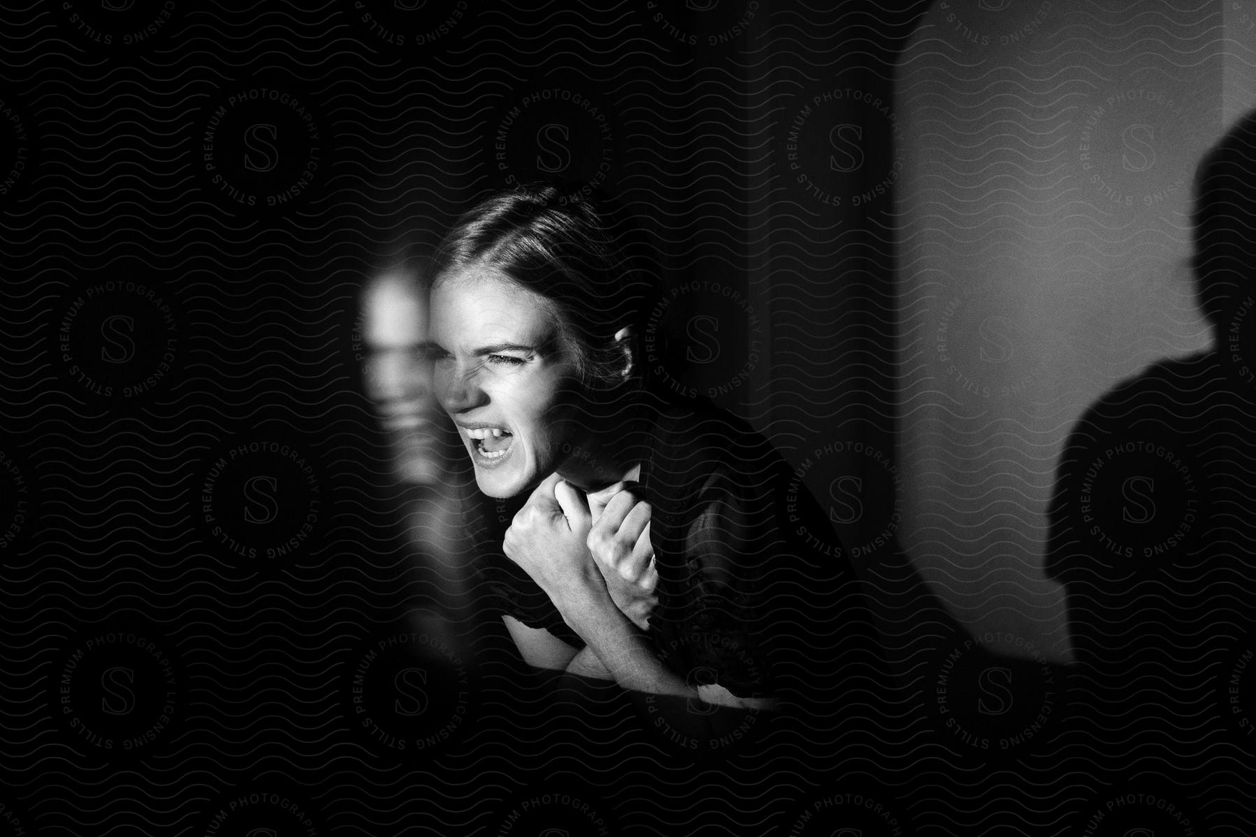 Young woman with clenched fists yelling in a dark room