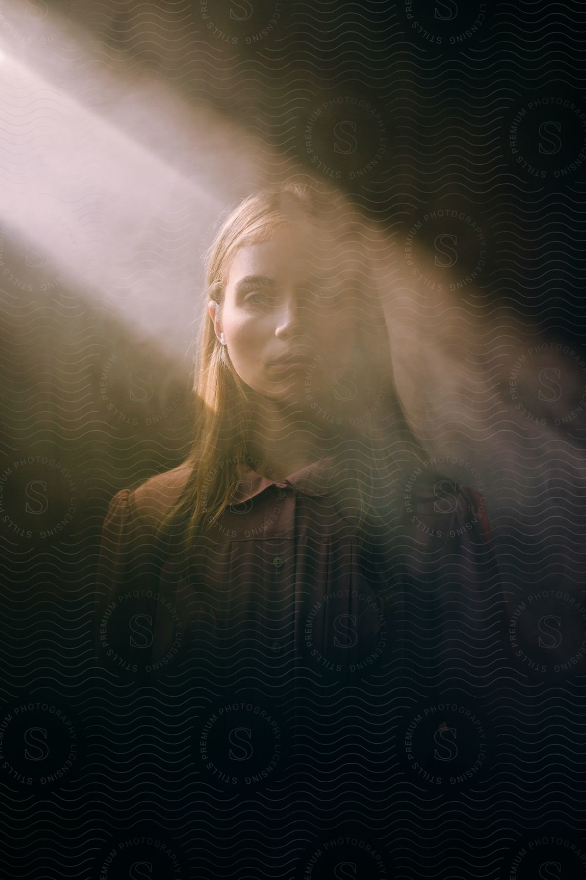 A sad girl in a blouse illuminated by the reflection of a light