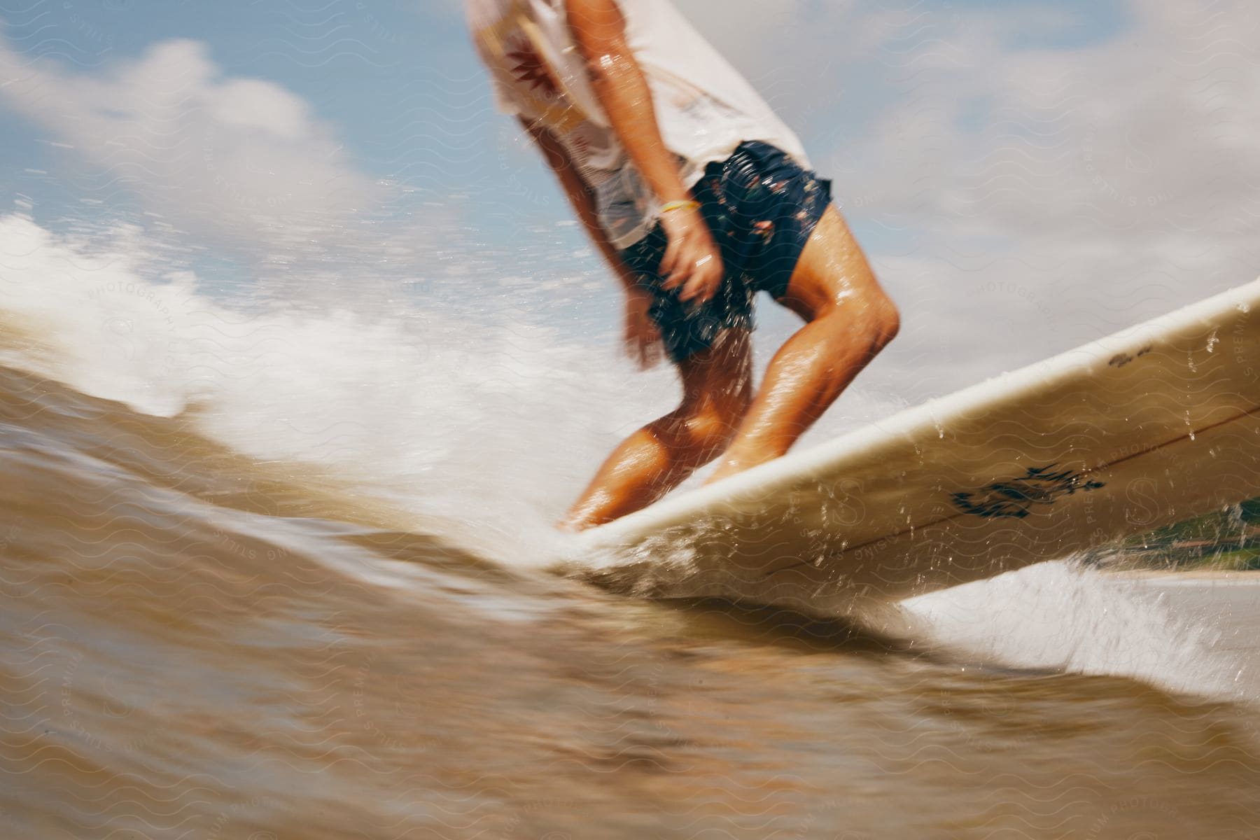 A person surfs in shorts and a tshirt at the beach