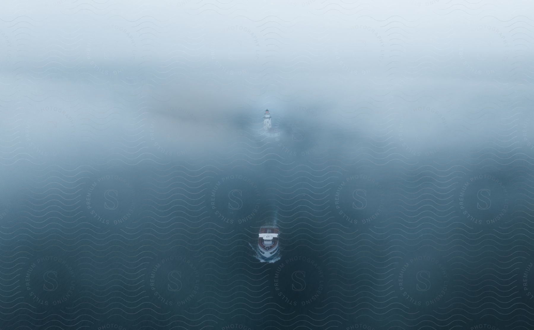 A boat sailing away from a lighthouse in dense fog