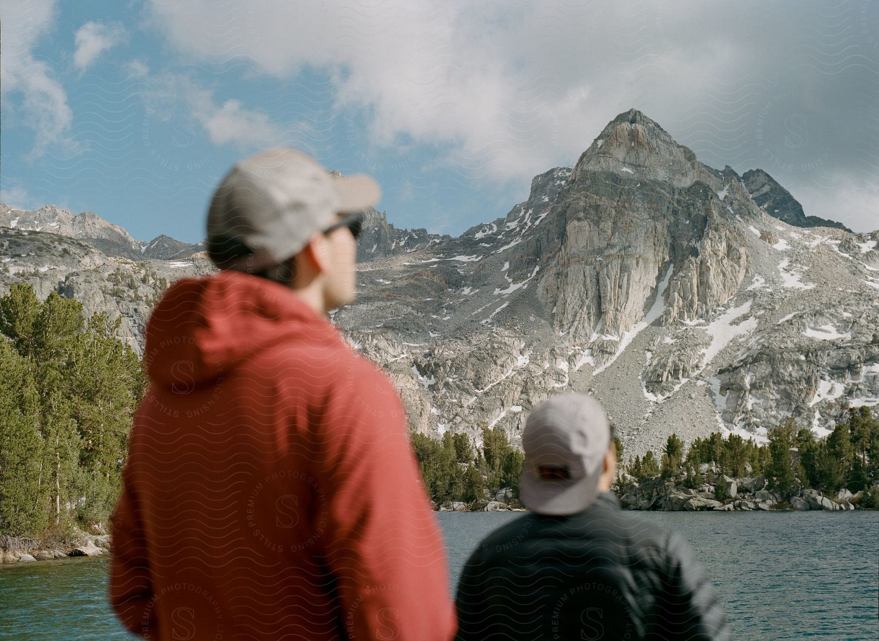 Two men standing near a lake with a mountain in the background