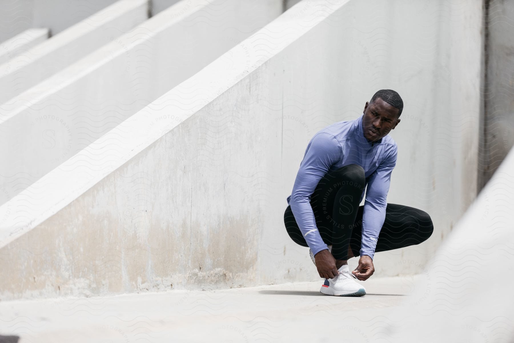 A man sitting on the floor wearing sportswear with a grey sleeve and knee