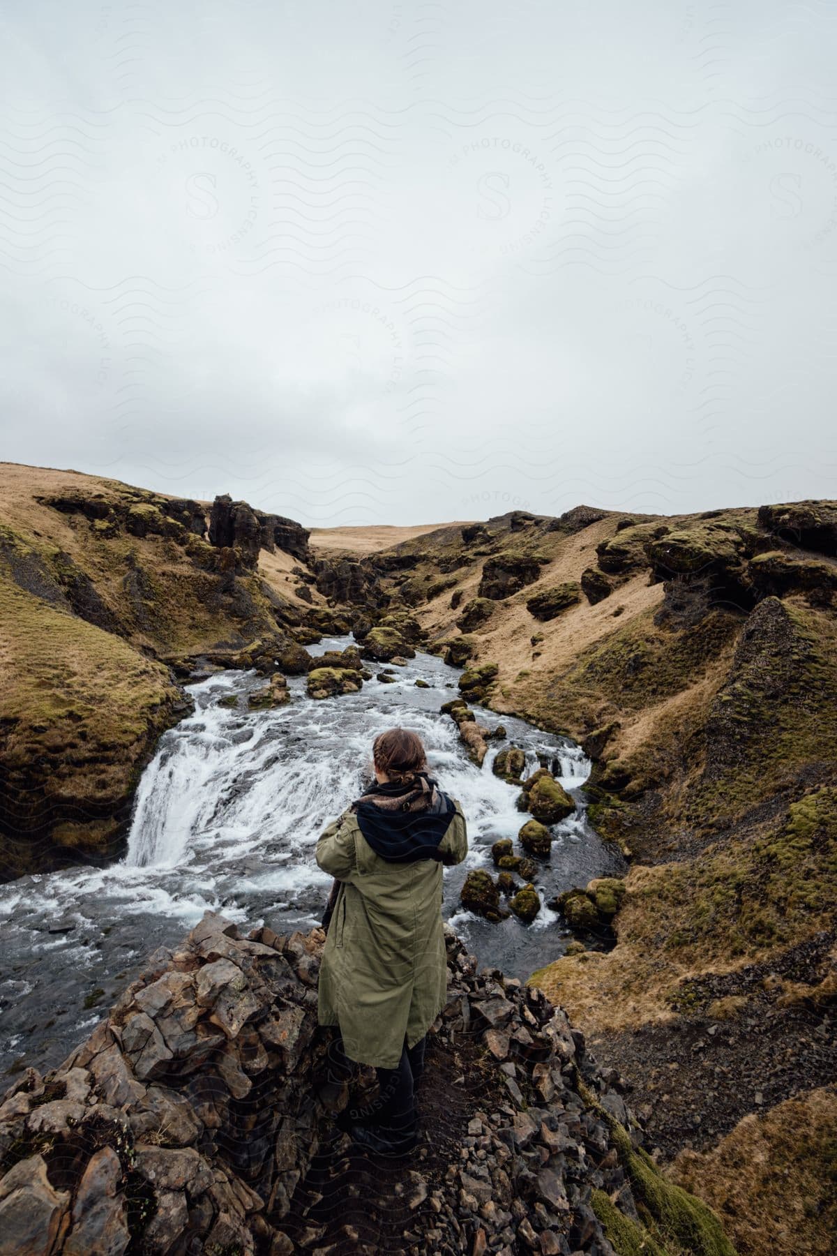 A woman standing on a mountain in front of a stream with scattered rocks