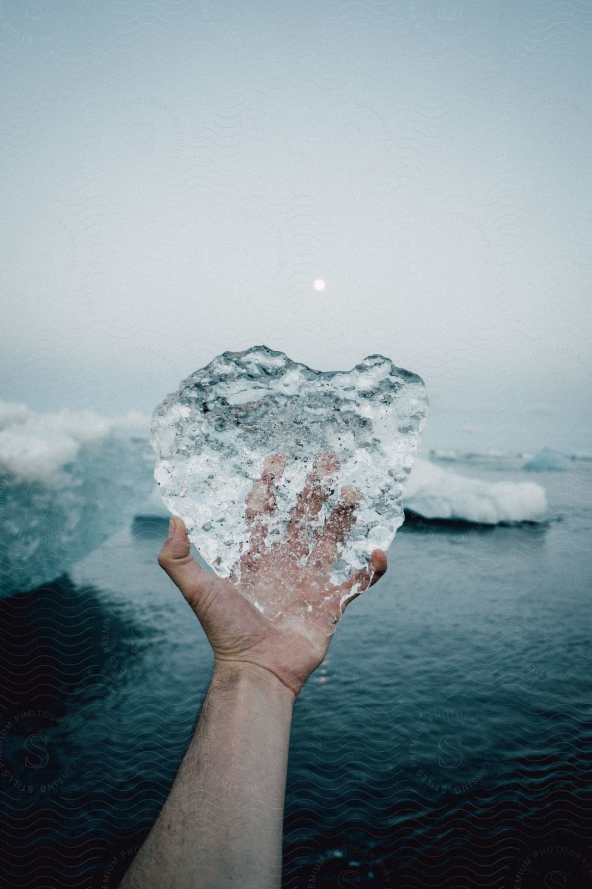 Hand holding ice against big ice fragments in iceland