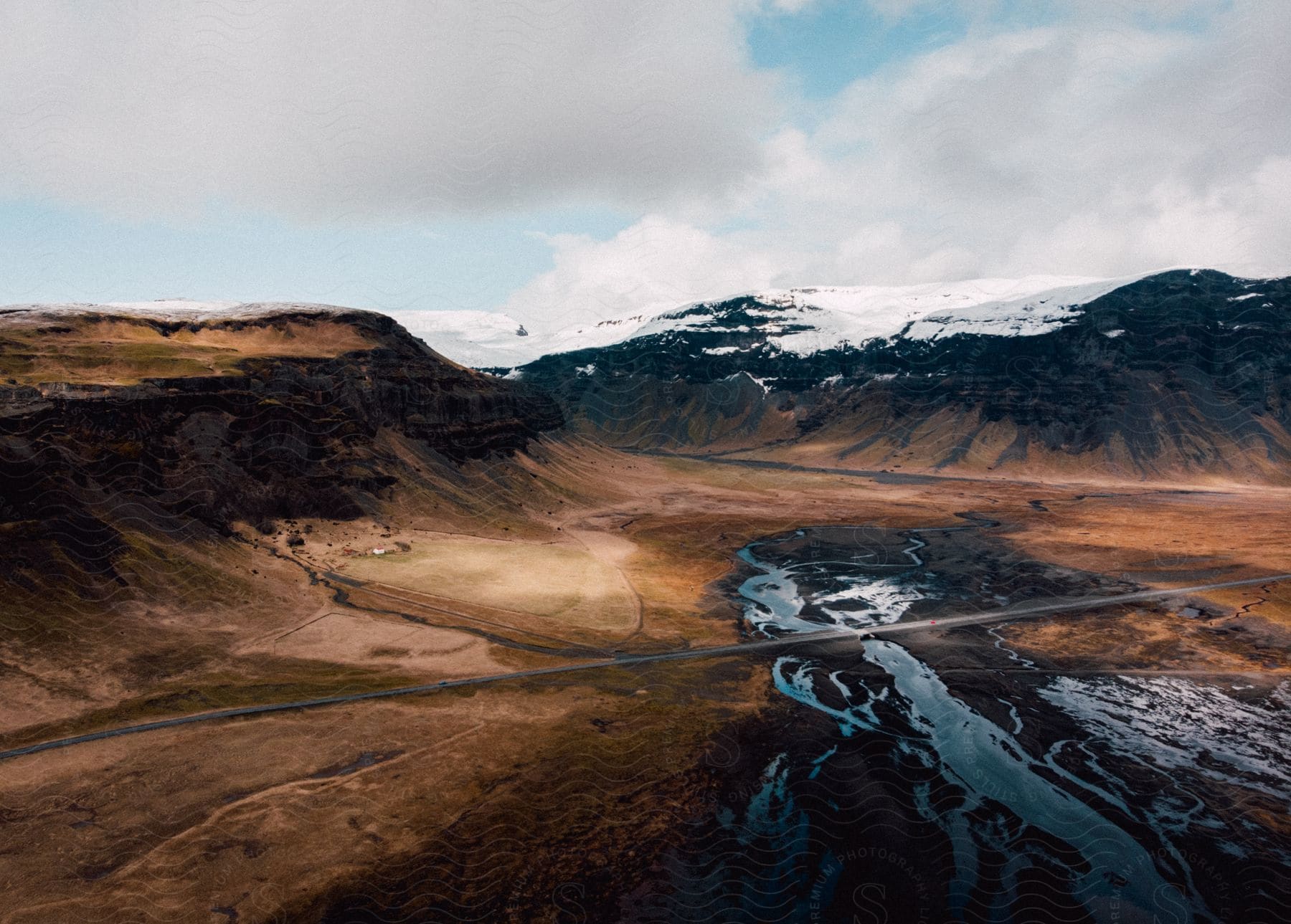 A road crosses over a creek in a valley of steep mountains on a cloudy day