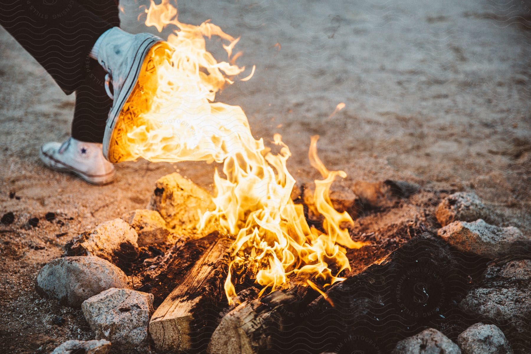 A shoe sole on flames near a campfire during the daytime