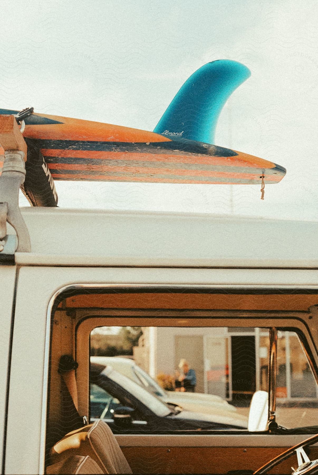 A closeup of an openwindowed van with a surfboard on top