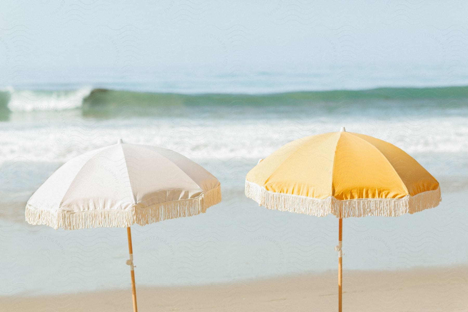 White and yellow beach umbrella against the wavy ocean