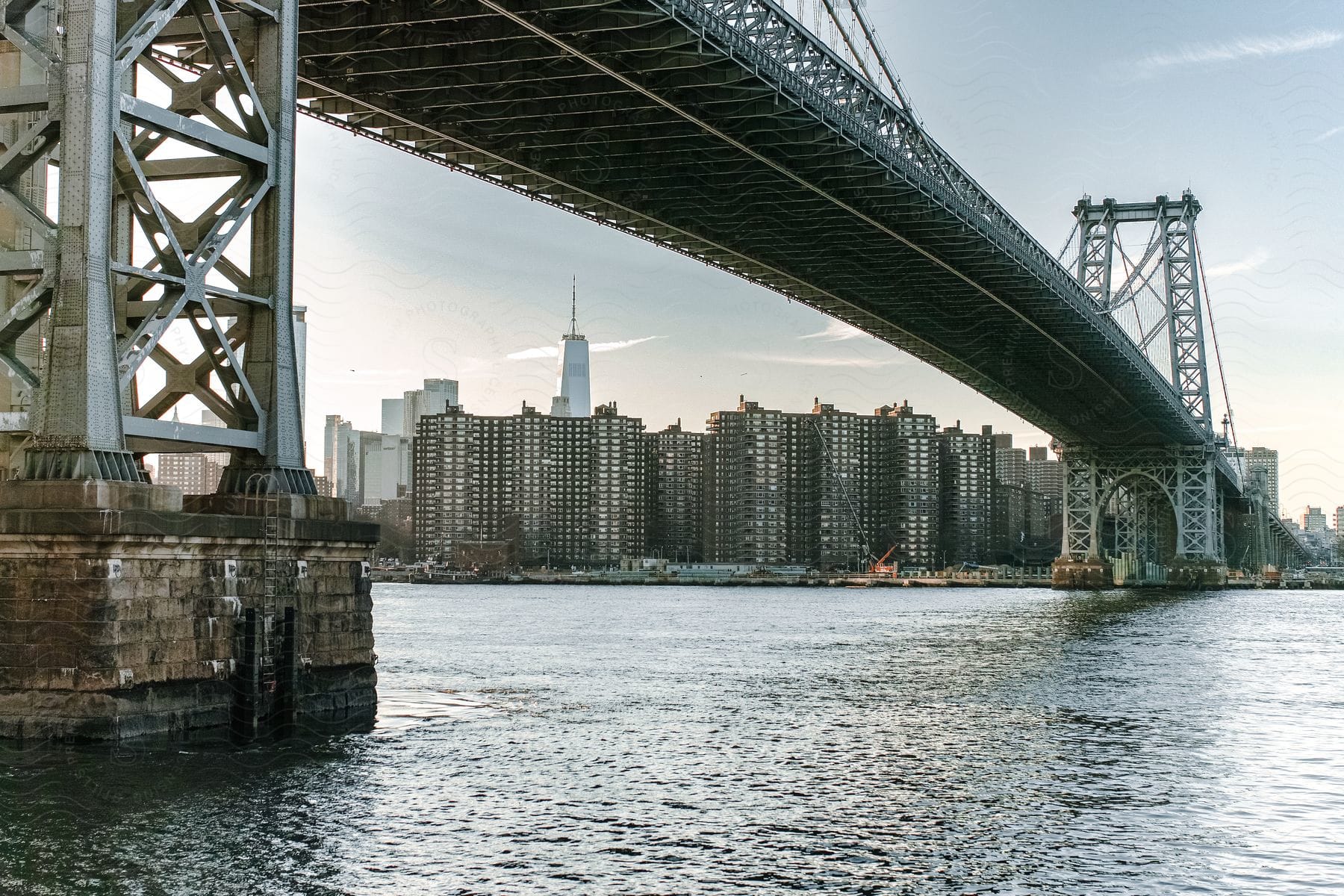 City shoreline and long bridge over water from ground level in daylight