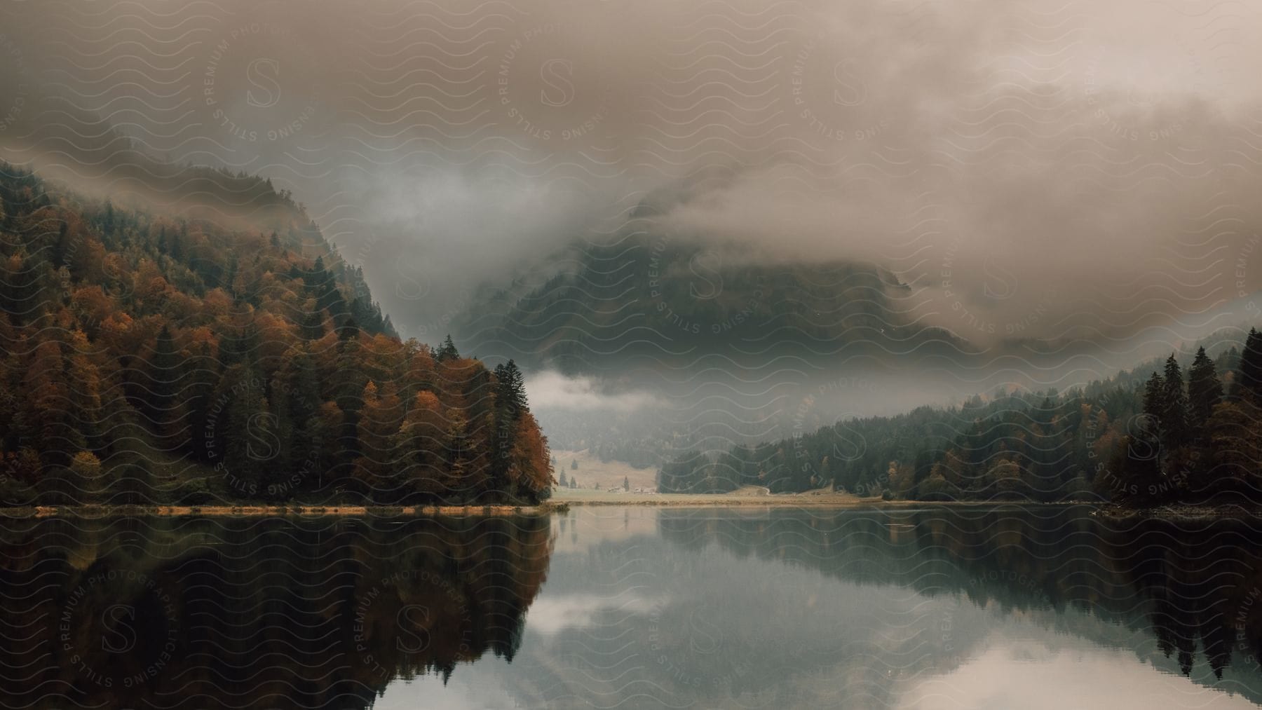 A calm lake under cloudy skies with forested land on two banks