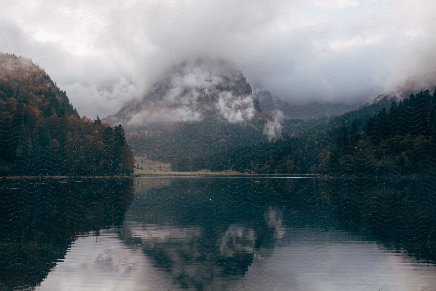 A lake surrounded by mountains changing leaves and storm clouds in the daytime