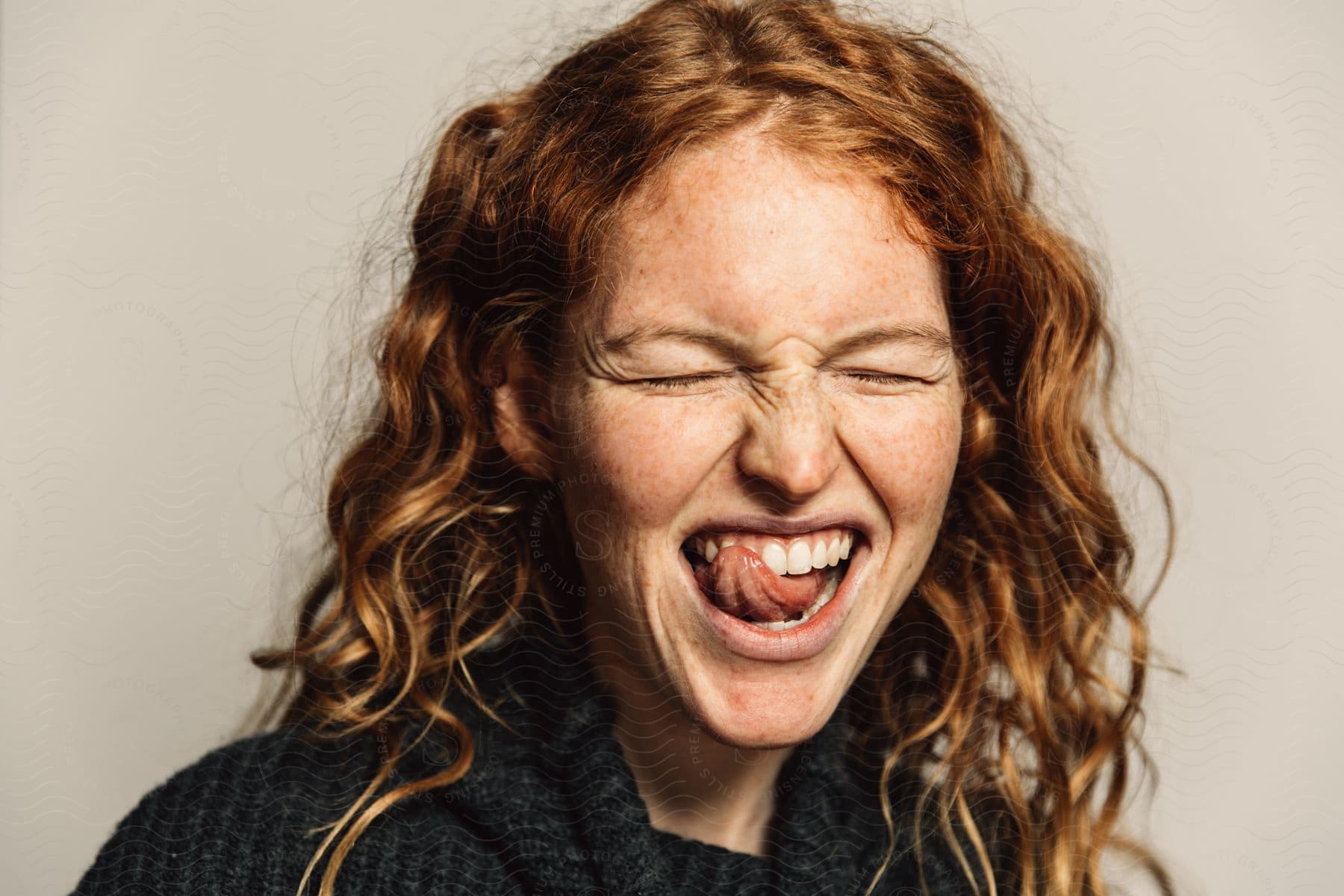 A woman squints her eyes while licking her teeth with her tongue