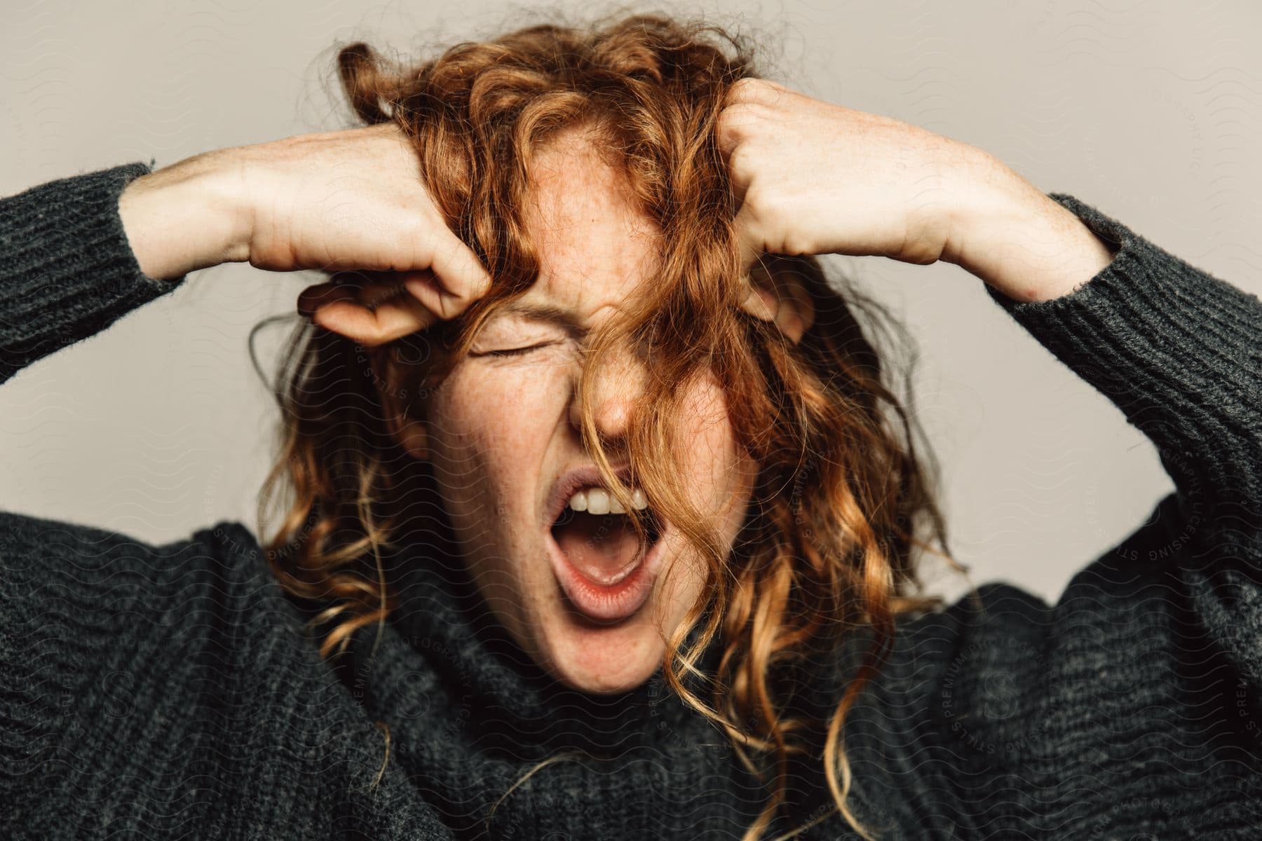 A woman scowling and yelling with her hands in fists on her forehead