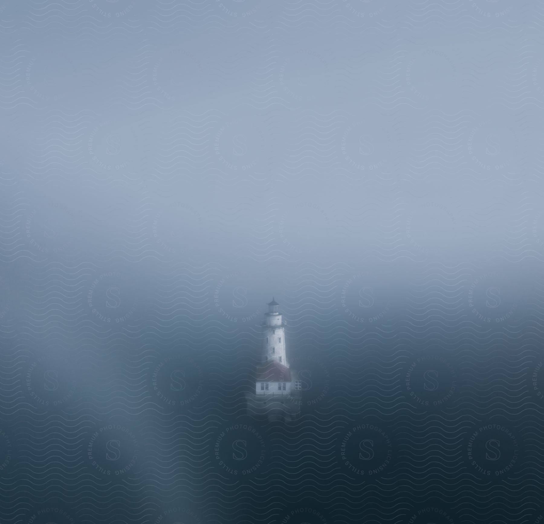 A lighthouse stands on a small island in the middle of the ocean