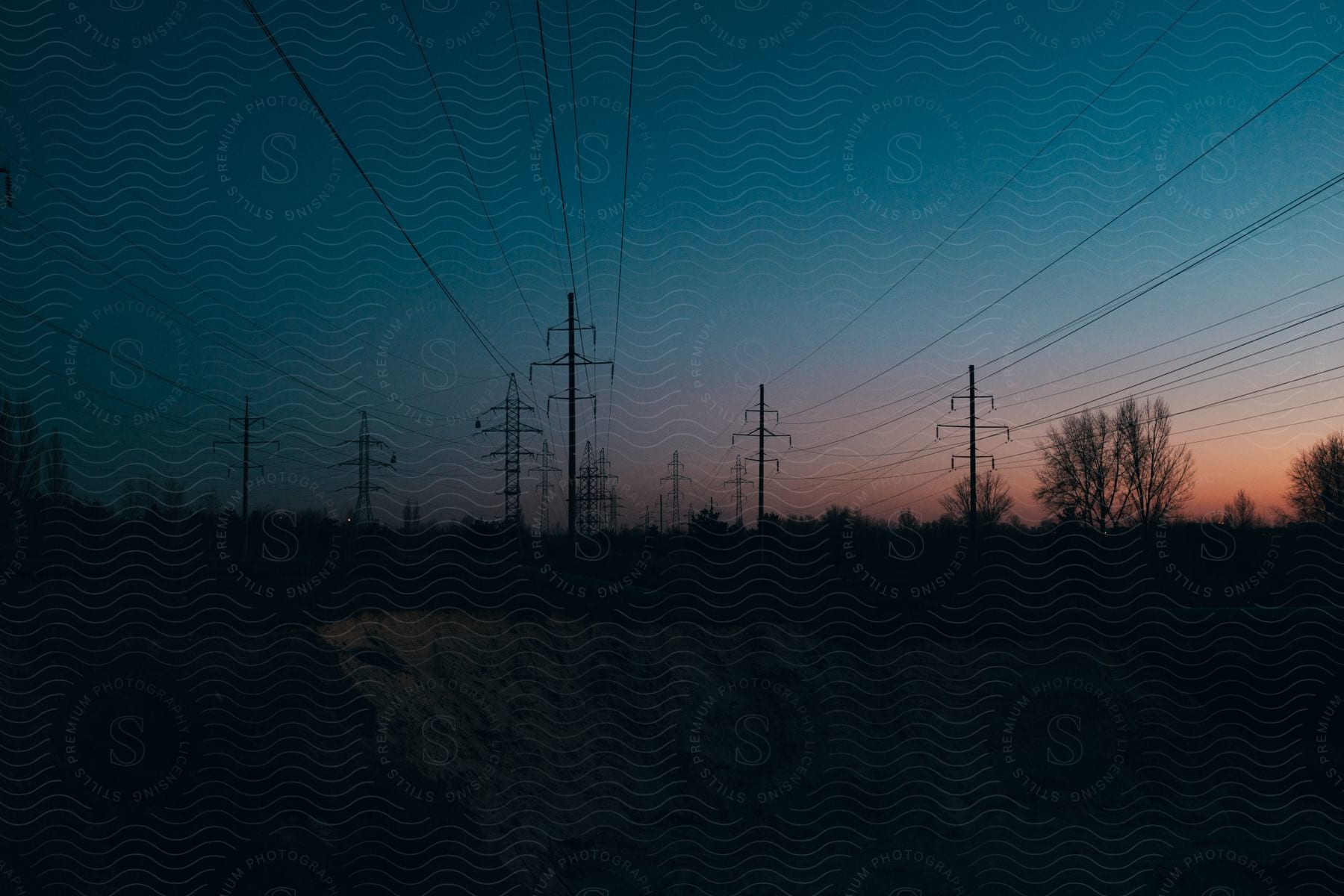 An overhead power line with a utility pole and transmission tower against a sky with clouds