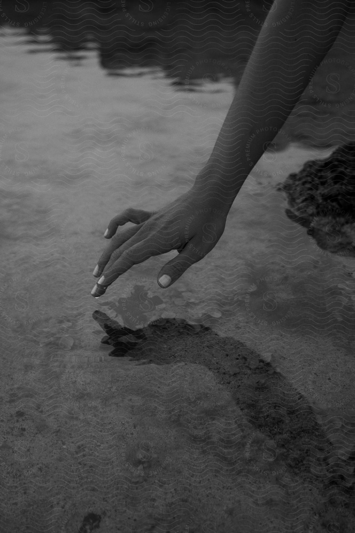 Hand of a woman hovering over the surface of a lake