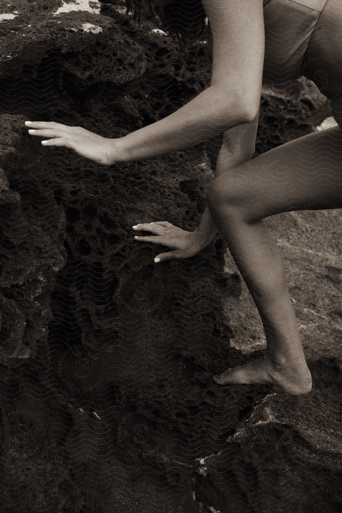 A woman climbs rocks on the beach