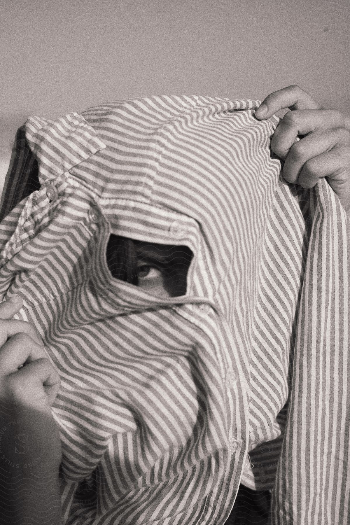 Person covering face with striped shirt showing only one eye