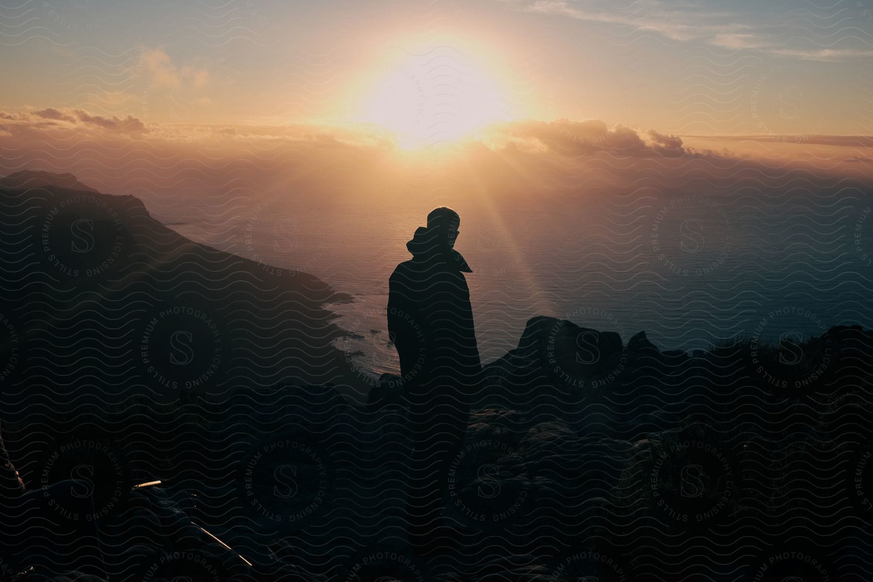 Hiking man standing on high ground next to the coast