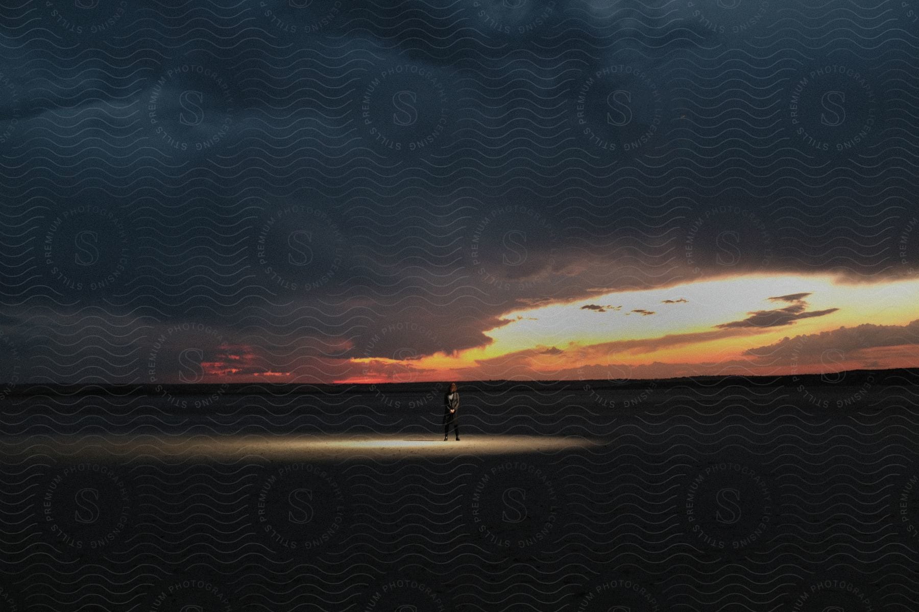 A Man Stands In A Dark Field At Dusk Surrounded By Darkness In A Spotlight