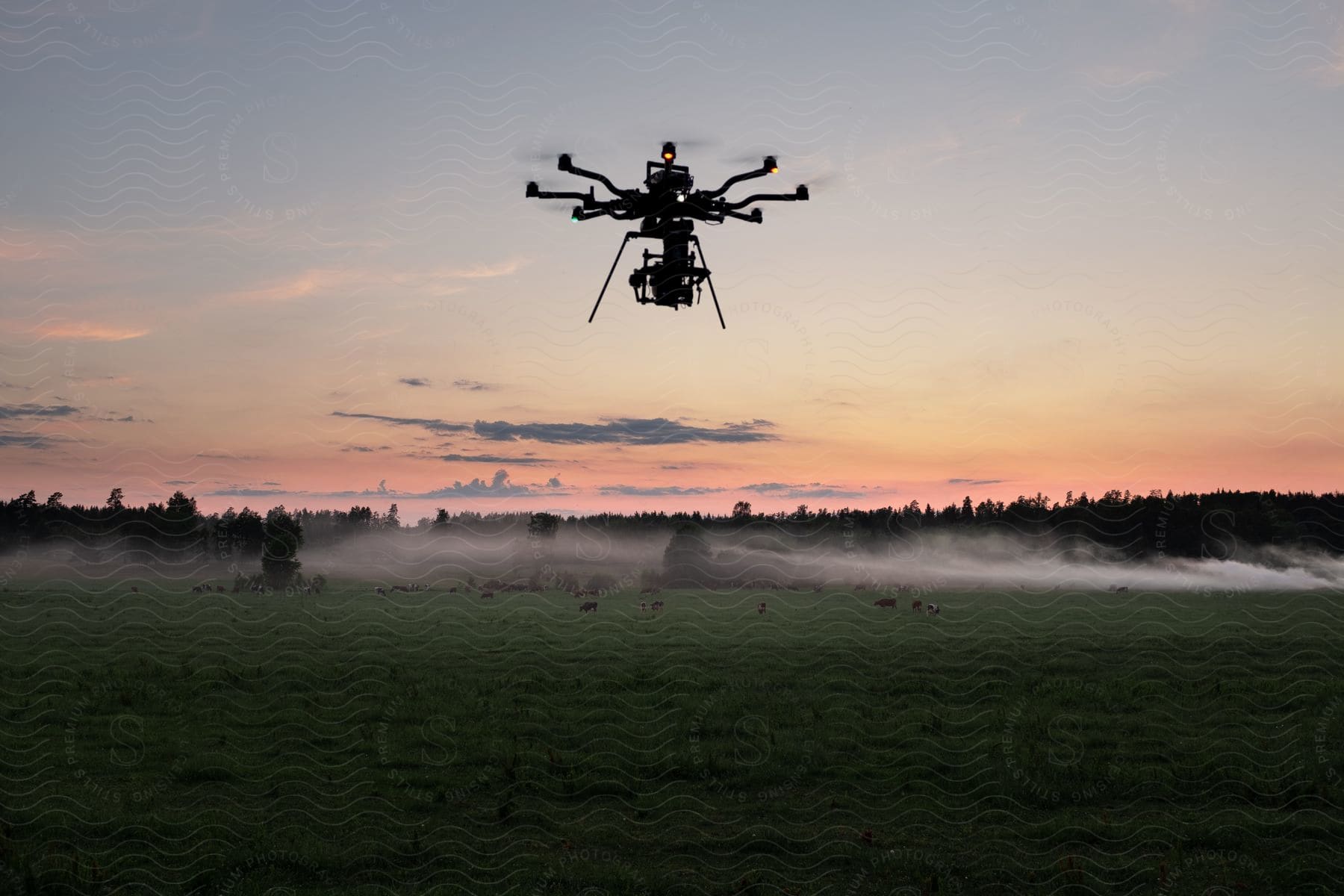 A helicopter drone with many propellers flies in the sky over a grassland