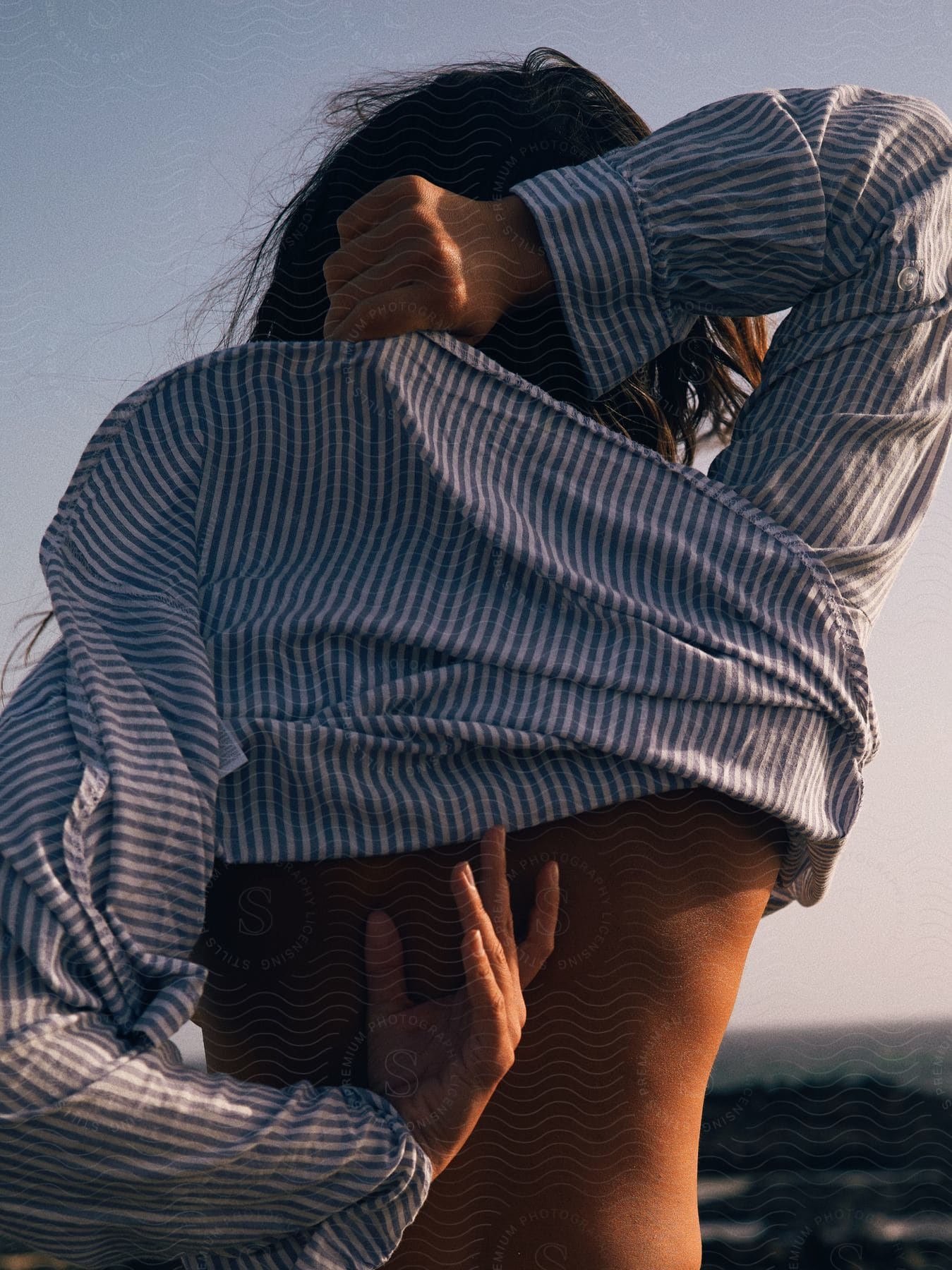 A woman adjusting her shirt outdoors at dusk