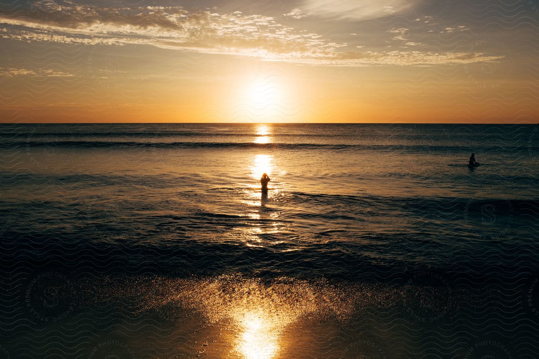 Two people swimming in the ocean at dawn