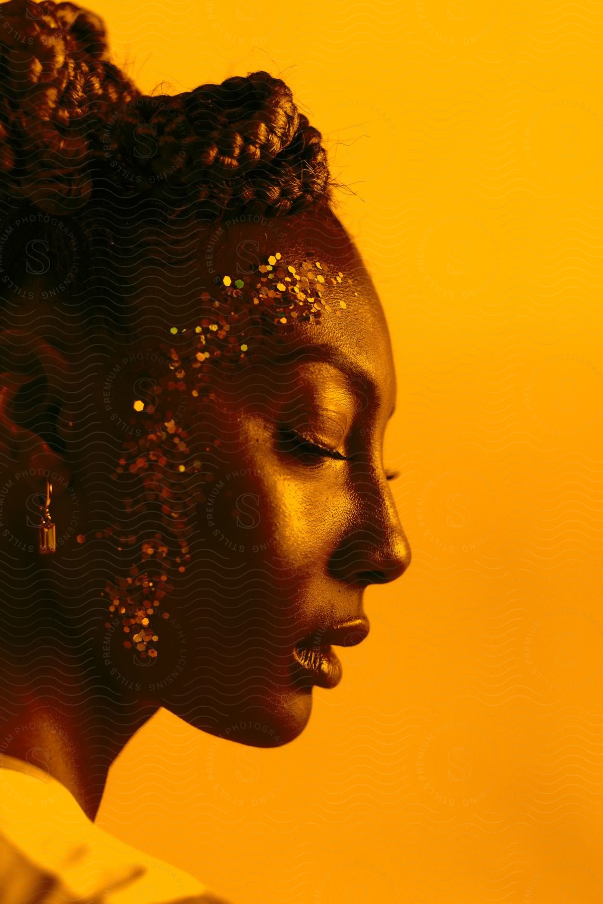 Woman with braided hair and yellow silk top standing against a yellow background